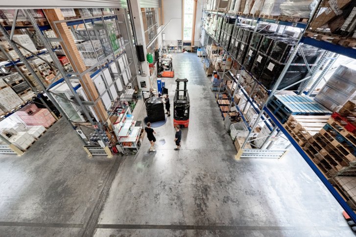 Rekken met drankkartons staan in een magazijn, vorkheftruck verplaatst zwarte pallet.