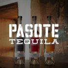 Drei Pasote Tequila-Flaschen stehen nebeneinander auf Holzoberfläche vor einer rustikalen Wand.