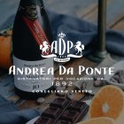 Flasche Wein steht neben Schokolade und Orangen auf einem Holztisch, Text "Andrea Da Ponte".