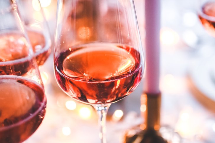 Rotwein in Gläsern, schimmernd, auf einem elegant gedeckten Tisch mit Kerzen und Geschirr.