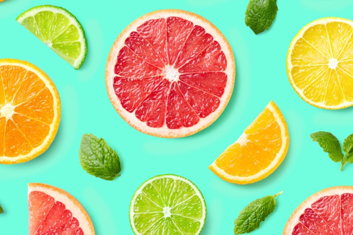 Zitrusscheiben liegen verstreut mit frischen Minzblättern auf hellem türkisfarbenem Hintergrund.