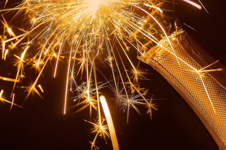 Eine Champagnerflasche sprüht Funken in die dunkle Umgebung.