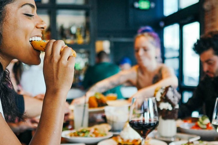 Personen essen und trinken an einem Tisch in einem belebten Restaurant.