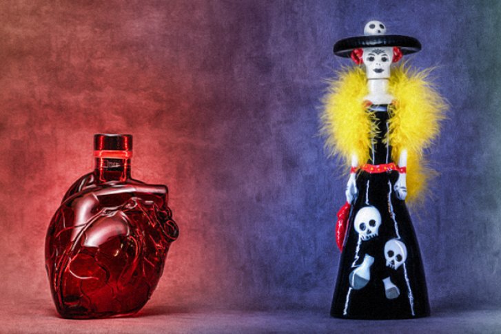 Vier Flaschen, kunstvoll gestaltet als Schädel, Herz, Skelettfigur und Kaktus, auf farbigem Hintergrund.