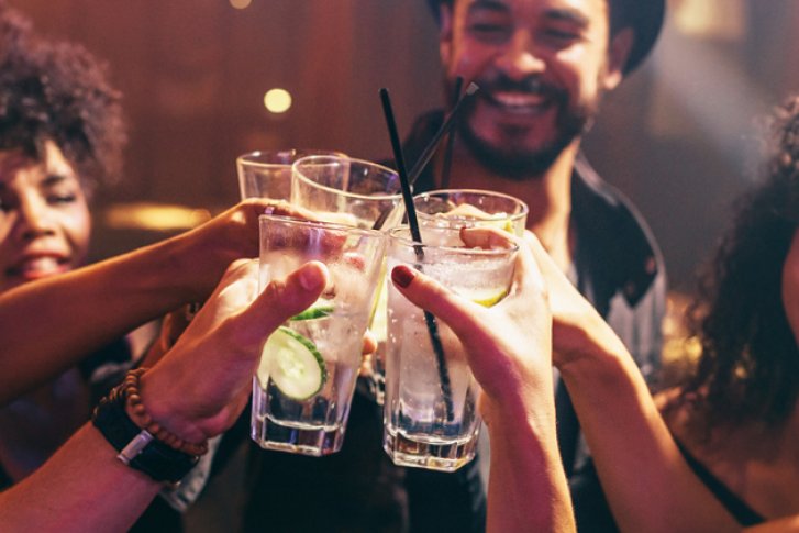 Menschen stoßen mit Gläsern an, feiern in einer lebhaften, beleuchteten Partyszene.