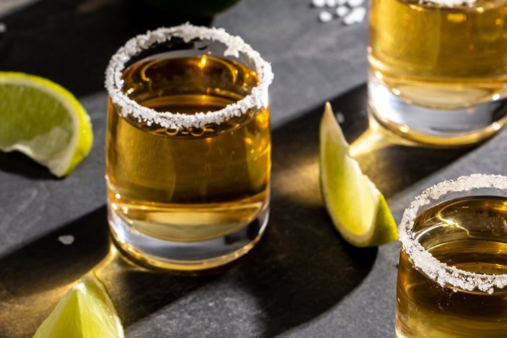 Gläser mit gesalzenem Rand stehen auf einer dunklen Oberfläche, umgeben von Limettenstücken.