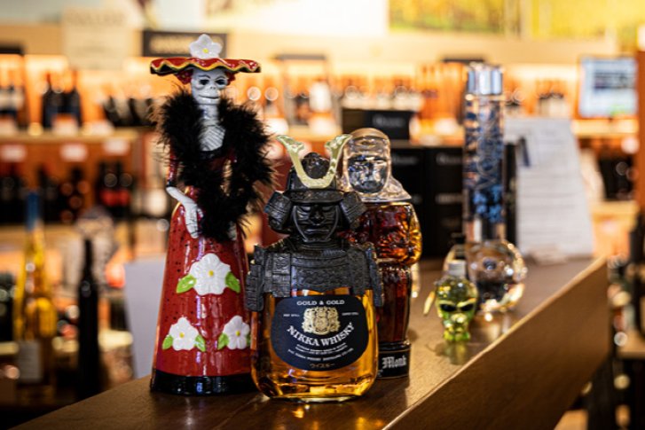 Flaschen in originellen Designs stehen dekorativ im gut beleuchteten Regal eines Weinladens.