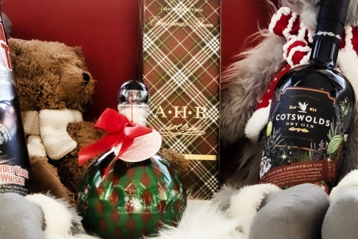 Flaschen und Geschenkverpackung mit Bären dekoriert auf einer weißen, flauschigen Oberfläche.