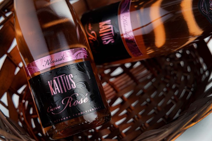 Zwei Roséweinflaschen liegen diagonal in einem braunen Korb, Etikett "Kattus Cuvée Rosé".