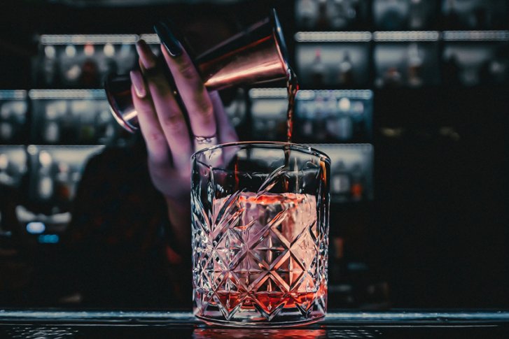 Glas mit Rotwein wird im dunklen, atmosphärischen Restaurant eingeschenkt.