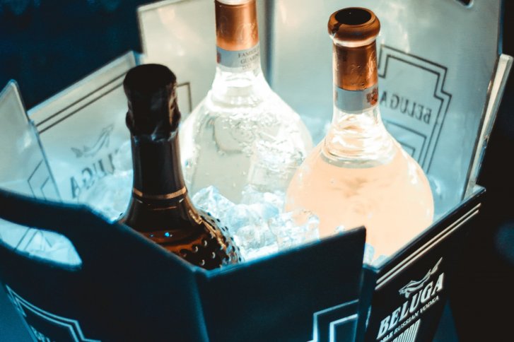 Flaschen stehen eisgekühlt in einem Beluga-Eimer, flankiert von Eiswürfeln.