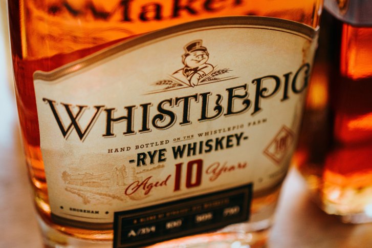 Flasche zeigt WhistlePig Rye Whiskey, 10 Jahre gereift, auf einer Holztischoberfläche.