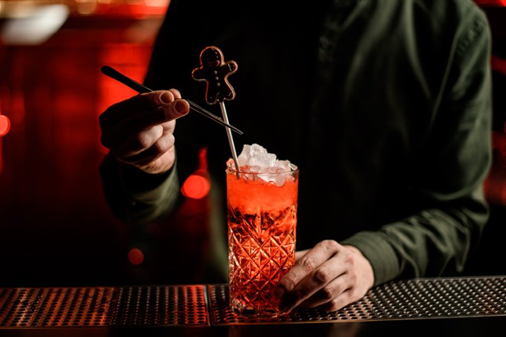 Ein rotes Getränk mit Eis und Lebkuchenmann-Dekoration wird in einer Bar serviert.