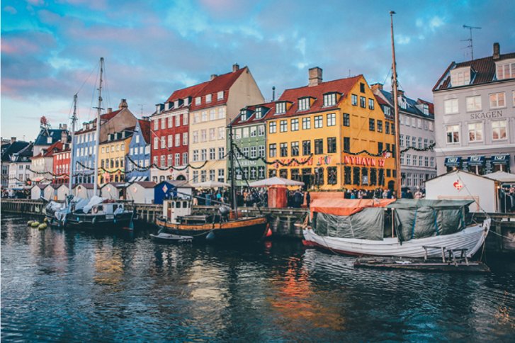 Bunte Häuser stehen entlang eines Kanals, mit Booten im Wasser und "Nyhavn 17" Schild.