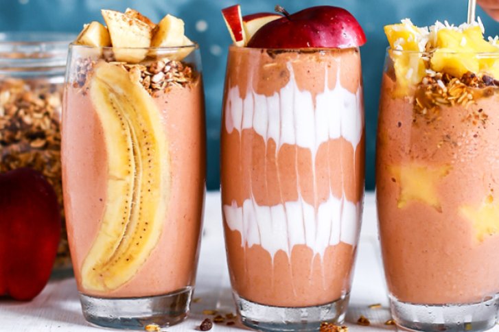 Drei Smoothies mit Obst und Müsli, dekorativ in Gläsern geschichtet, auf hellem Untergrund.