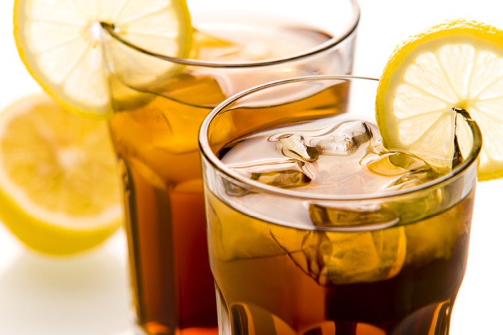 Zwei Gläser Eistee mit Zitronenscheiben, stehen auf einem weißen Untergrund.