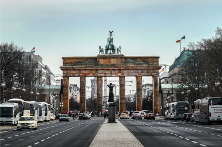 Das Brandenburger Tor steht majestätisch in einer belebten Straße mit Autos und Bussen.