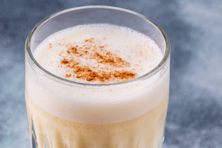 Golden Cadillac im Glas mit Strohhalm auf blauem Hintergrund.