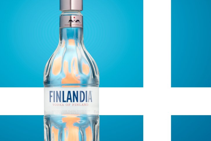 Eine Wodka-Flasche steht vor einem blau-weißen Hintergrund mit dem Text "FINLANDIA" sichtbar.