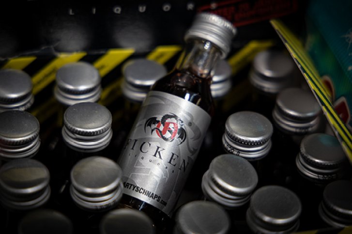 Eine Flasche Likör steht in einer Kiste mit mehreren weiteren Flaschen ähnlicher Größe.