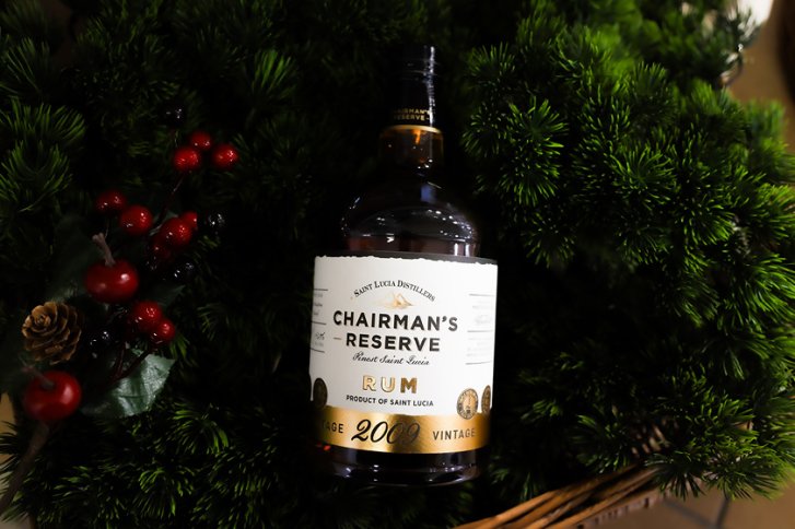 Flasche „Chairman's Reserve Rum“ ruht in einem grünen Kranz mit roten Beeren und Zapfen.