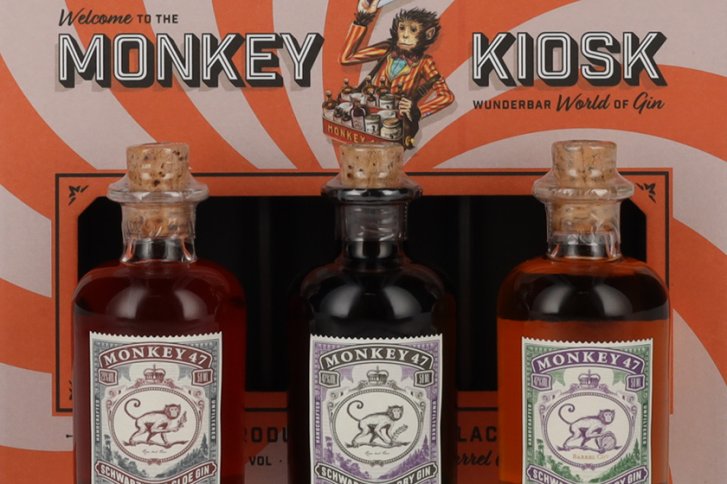 Drei Gin-Flaschen mit Korken stehen vor einer Verpackung mit „Monkey Kiosk“ Beschriftung.