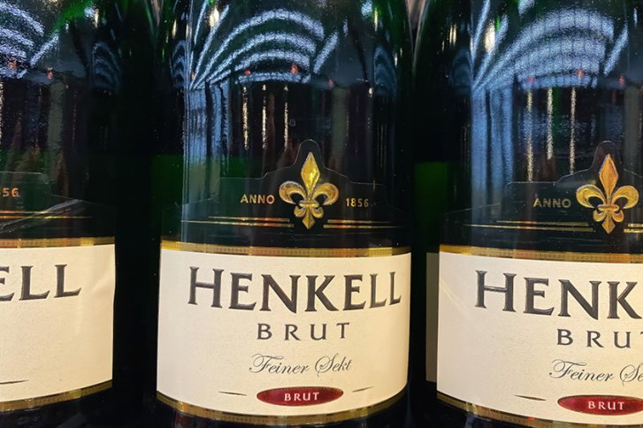 Flaschen mit Etikett "Henkell Brut, Feiner Sekt." Stehen dicht nebeneinander im Regal.