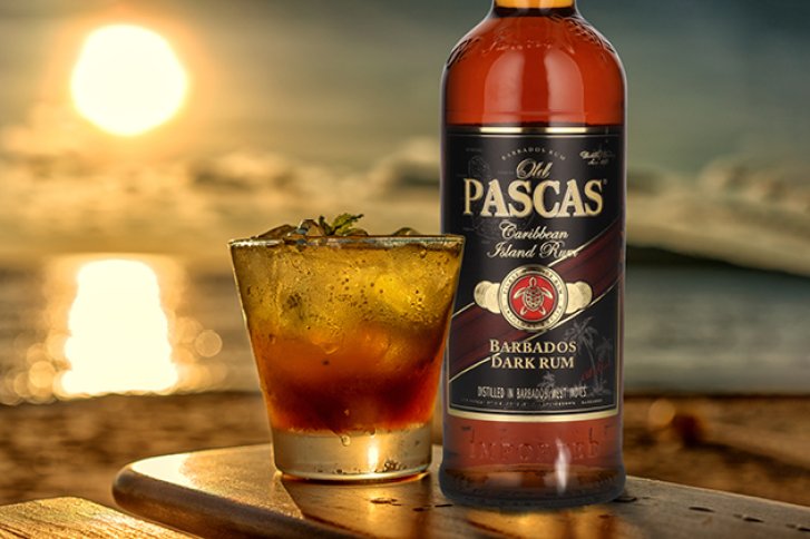 Rumflasche und Cocktail stehen auf Tisch am Strand, Sonnenuntergang im Hintergrund, warme Farbtöne.