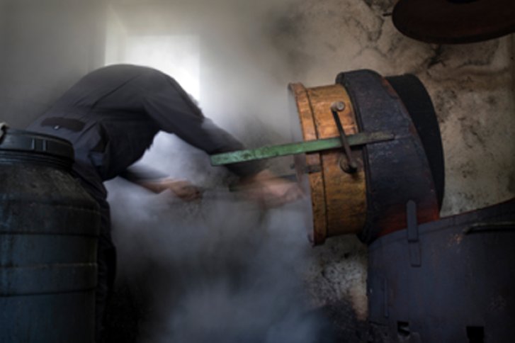 Person bearbeitet dampfende Maschine in einem rustikalen, industriellen Raum.