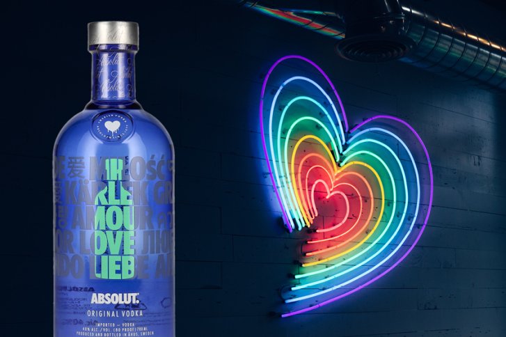 Blaue Absolut-Vodka-Flasche mit Liebeswörtern, daneben neonfarbenes, leuchtendes Herz an Ziegelwand.