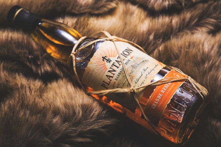 Eine Rumbottle liegt auf braunem Fell, etikettiert mit "Plantation" und "Grande Reserve".