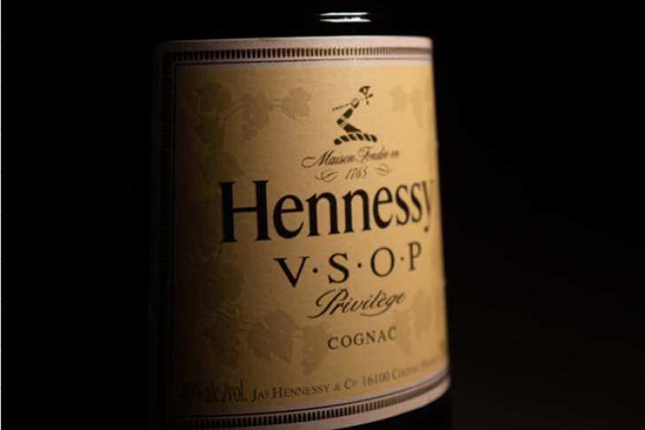 Flasche mit Etikett zeigt „Hennessy V.S.O.P Privilege Cognac“ in dunkler, schattiger Umgebung.