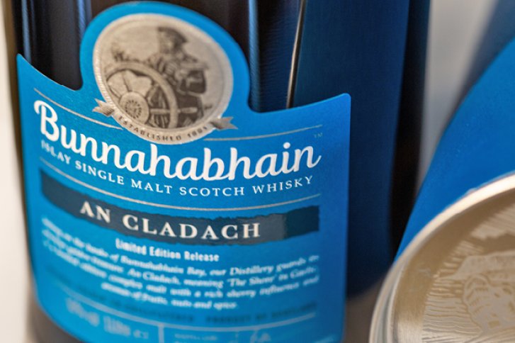 Eine Whiskyflasche mit blauem Etikett steht neben einer geöffneten Dose.