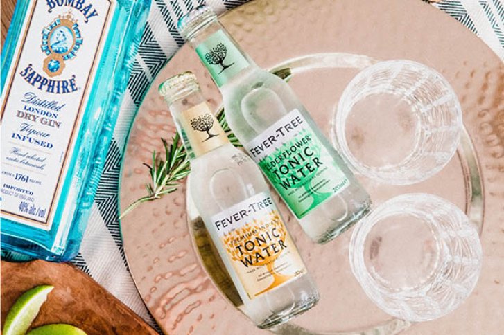 Zwei Fever-Tree-Wasserflaschen liegen auf einem Tablett, neben einem Bombay Sapphire Gin.