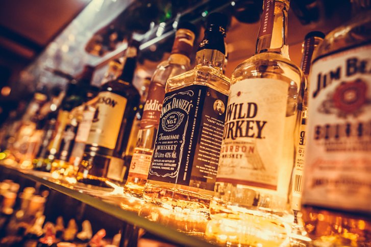 Flaschen stehen nebeneinander, leuchten auf Regal, umgeben von sanfter Barbeleuchtung.