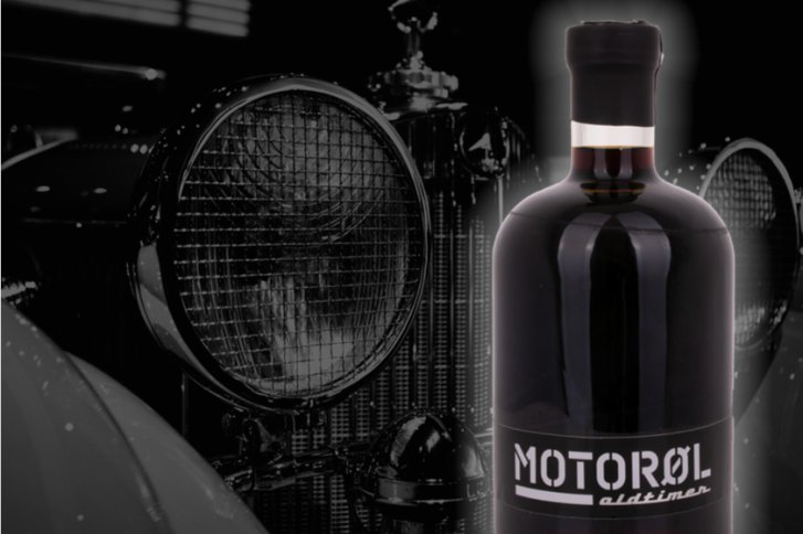 Flasche steht vor altem Auto, mit "MOTORØL" beschriftet und starker Schwarzweiß-Kontrast.