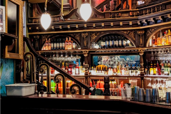 Barregal voller Flaschen, elegant beleuchtet, in einem stilvollen, historischen Ambiente mit Holzverzierungen.