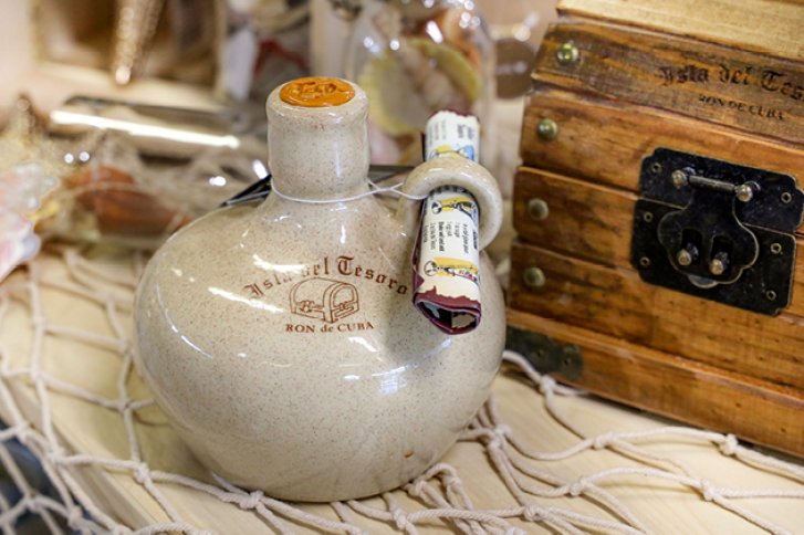 Keramikflasche steht auf Netz, daneben eine Holztruhe, etikettiert mit "Isla del Tesoro Ron".