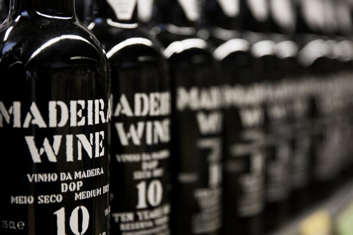 Flaschen mit "Madeira Wine" stehen in einer Reihe im Regal.