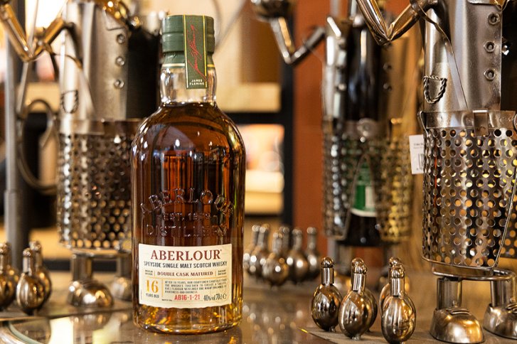 Flasche Aberlour Whisky steht auf Tisch, umgeben von metallischen Figuren in gemütlichem Ambiente.