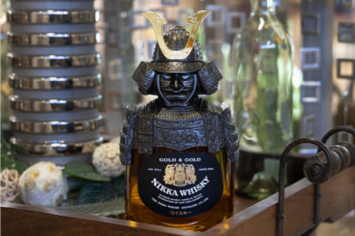 Eine Samurai-Flasche enthält Nikka Whisky; sie steht dekorativ auf einem Holztisch im Innenraum.