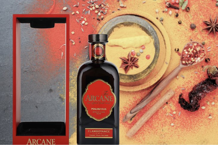 Flasche Rum steht neben leerer Verpackung auf einem Hintergrund aus Gewürzen und rotem Pulver.