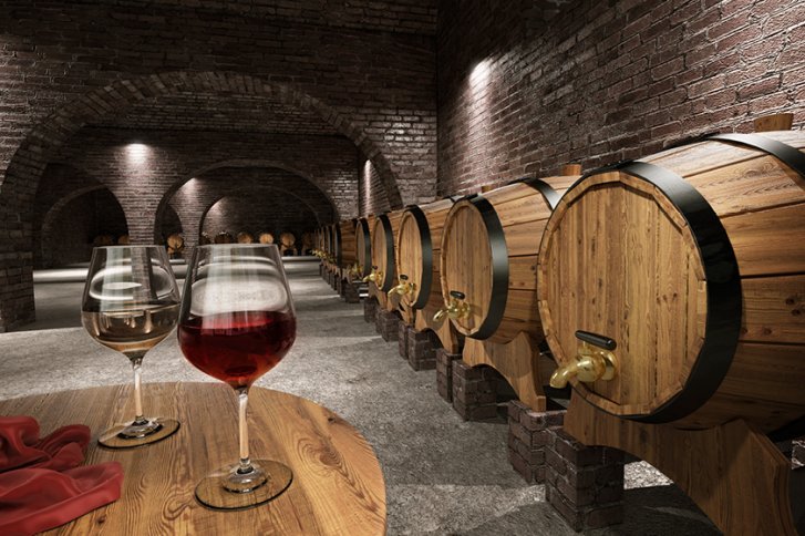 Zwei Weingläser stehen auf einem Holztisch im steinernen Weinkeller mit Holzfässern.