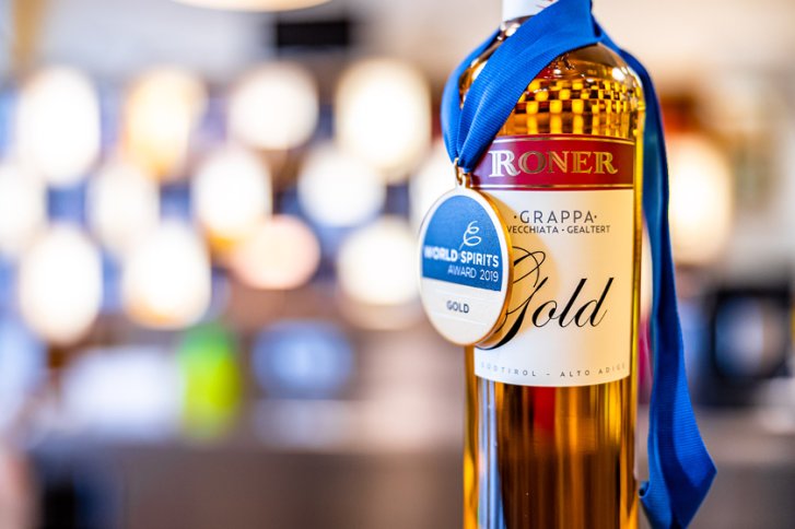 Flasche mit Grappa - trägt Medaille - in unscharfer, beleuchteter Umgebung.