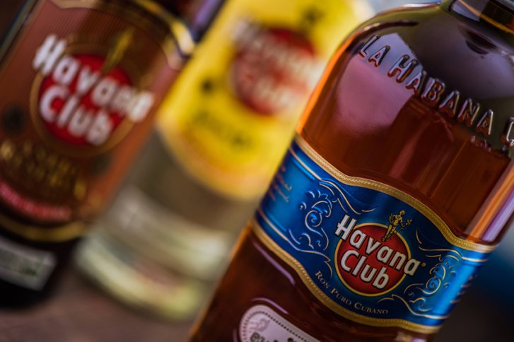 Flasche Rum steht im Vordergrund, unscharfe andere Flaschen im Hintergrund, "Havana Club" Logo sichtbar.