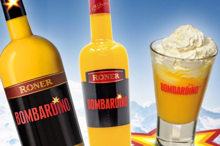 Zwei gelbe Bombardino-Flaschen und ein Glas mit Sahne stehen vor winterlicher Bergkulisse.