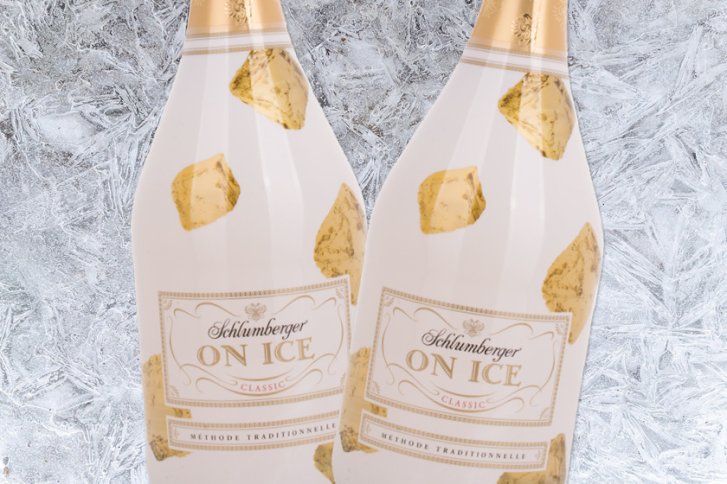 Zwei Champagnerflaschen mit goldenen Akzenten stehen vor einem eisartigen Hintergrund. "Schlumberger ON ICE".