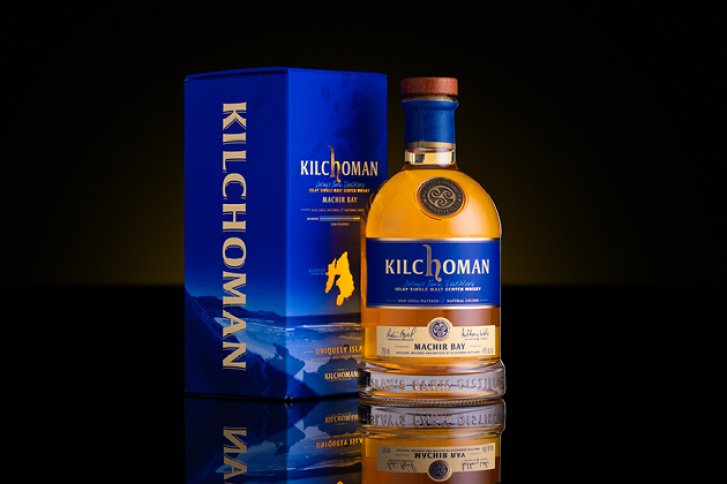 Eine Whisky-Flasche mit blau-goldener Verpackung steht auf reflektierender schwarzer Oberfläche.