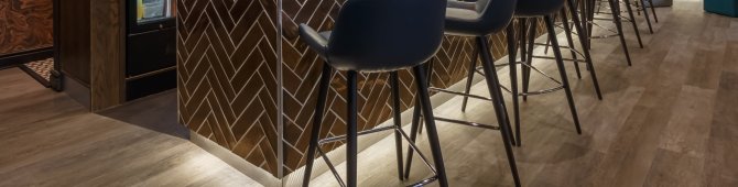 Bar with seven stools, decorative lamps, drinks and shelves, modern ambience in the interior.