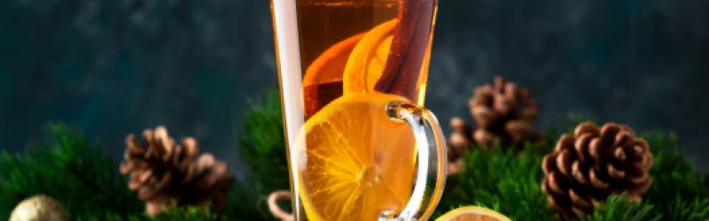 Grog mit Orangenund Tannenzweigen im Hintergrund